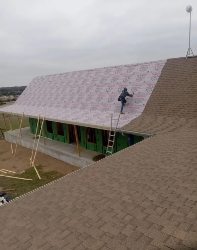 Worker preparing underlayment for a metal roof installation in Zion